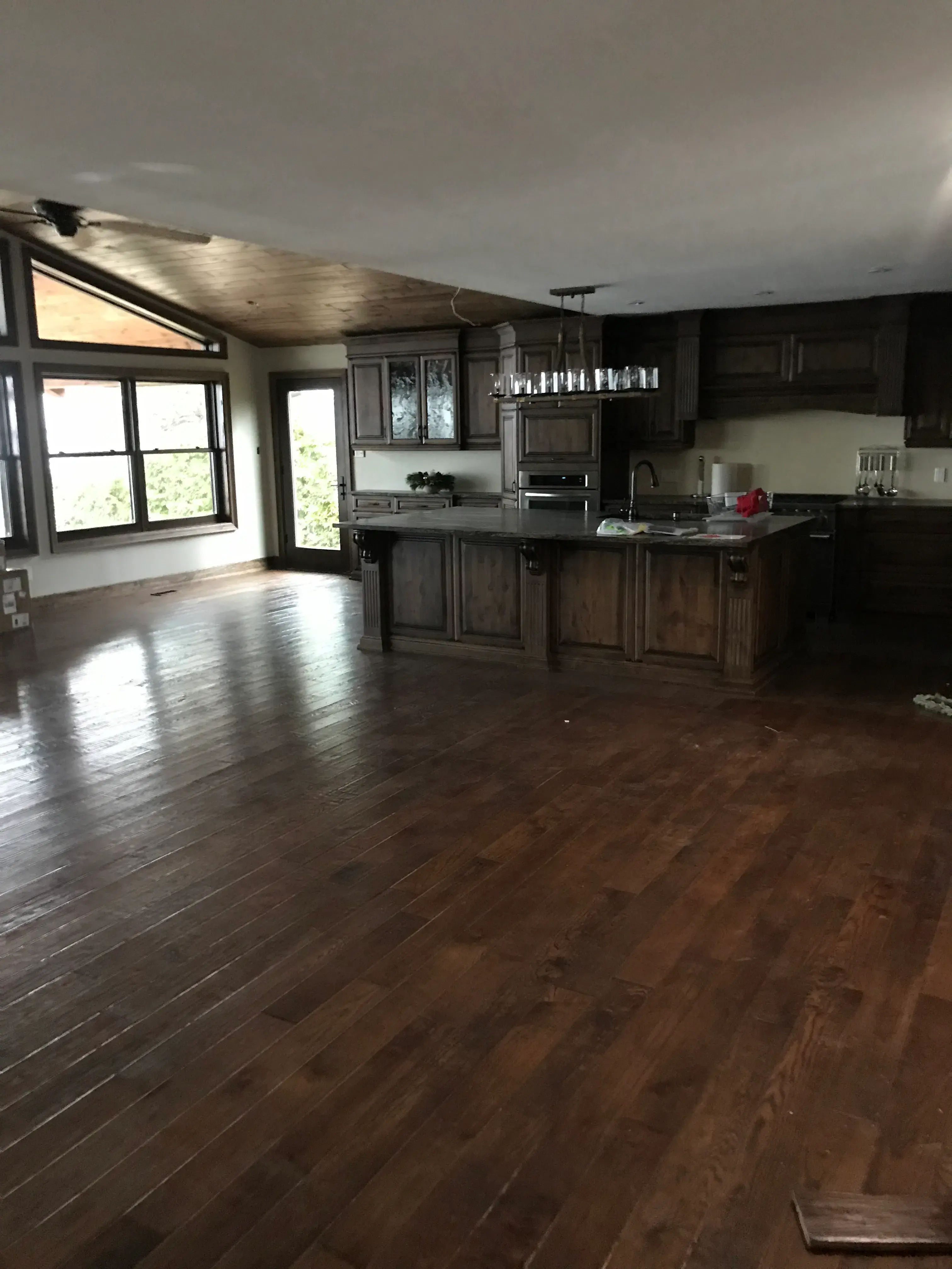 Dark hardwood floor extending through an open kitchen and living area